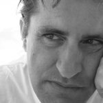 Retrato a preto e branco, em grande plano, de um homem com o rosto apoiado na mão. Não há texto visível que permita identificá-lo.