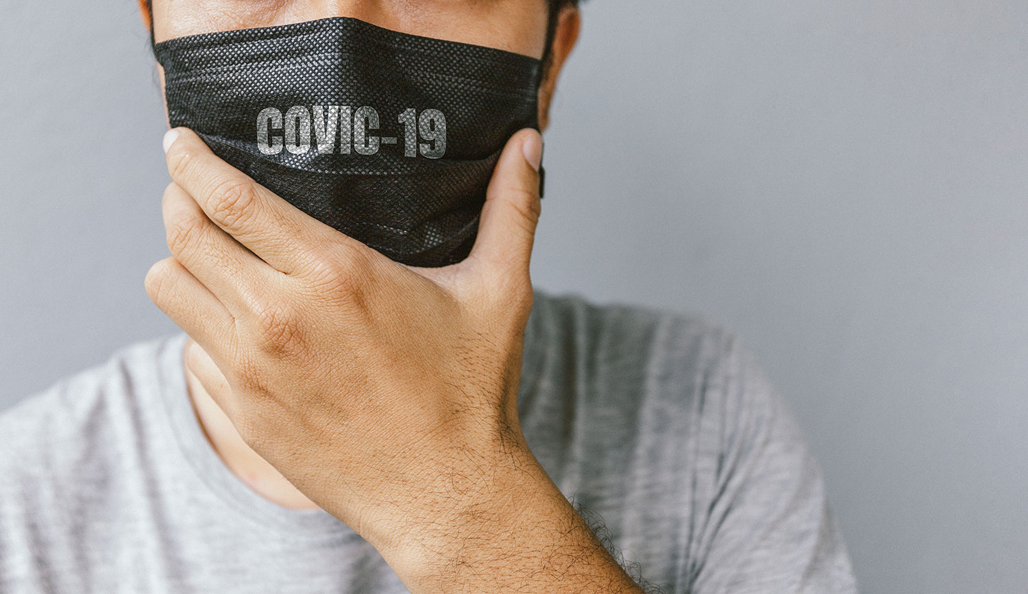 homem usando máscara preta coma inscrição de covid-19