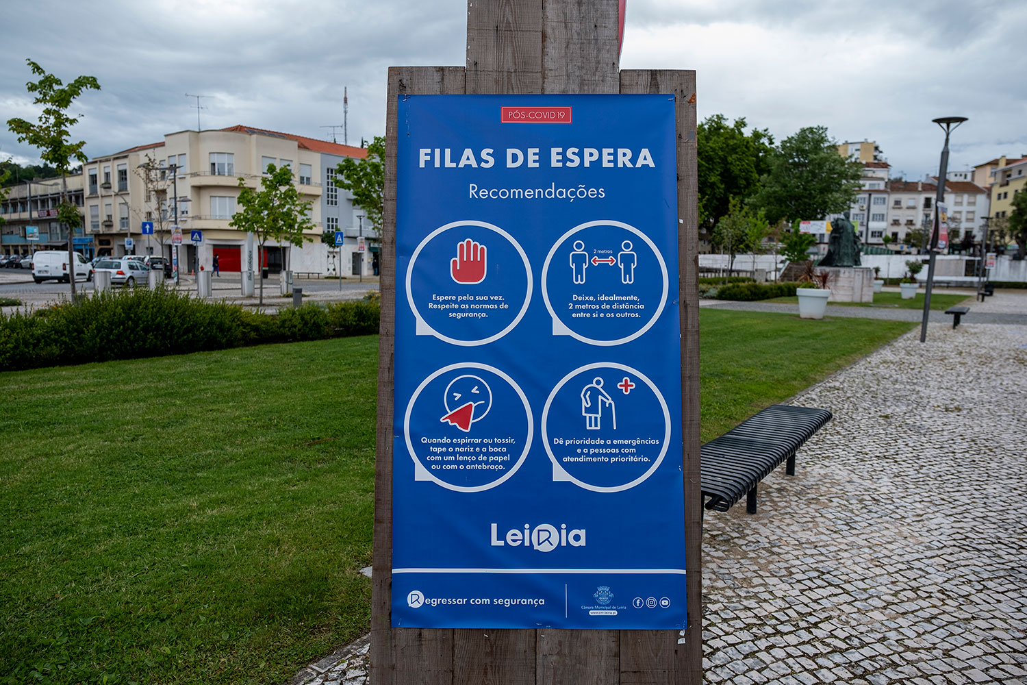 Cartaz em Leiria com recomendações para filas de espera no período pós-COVID-19. Indica que se deve respeitar a distância de dois metros, tapar a boca e o nariz ao tossir ou espirrar e dar prioridade a emergências.