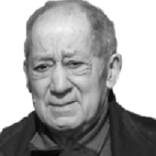 Retrato a preto e branco de um homem idoso, de frente, com expressão séria. Veste roupa escura.