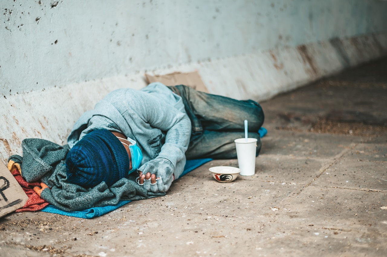 homem sem-abrigo deitado numa rua numa cidade