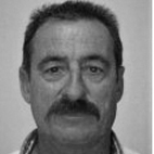 Retrato a preto e branco de um homem com cabelo curto e bigode, fotografado de frente sobre um fundo claro.