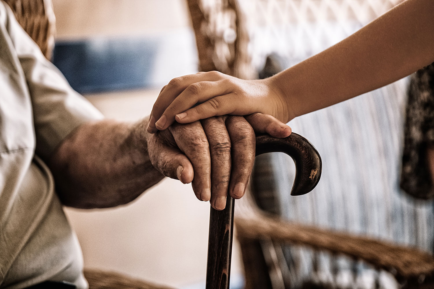 imagem de uma funcionária de lar a segurar a mão de um utente idoso