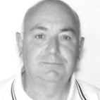 Retrato a preto e branco de um homem, de frente para a câmara, sobre fundo claro. Veste uma camisola de gola com riscas.