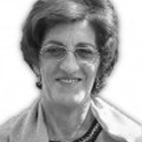 Retrato a preto e branco de uma mulher com óculos, a sorrir ligeiramente. É visível da cabeça aos ombros, sobre um fundo claro.