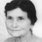Retrato a preto e branco de uma mulher, fotografada de frente. A imagem mostra o rosto e parte dos ombros.