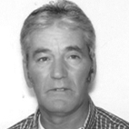 Fotografia de rosto, a preto e branco, de um homem de cabelo grisalho e camisola aos quadrados, sobre fundo claro. Não há texto visível que permita identificá-lo.