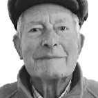 Retrato a preto e branco de um homem idoso, de frente para a câmara, com boina e casaco.