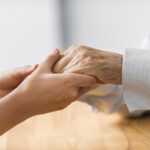 enfermeira segurando as mãos de um utente idoso
