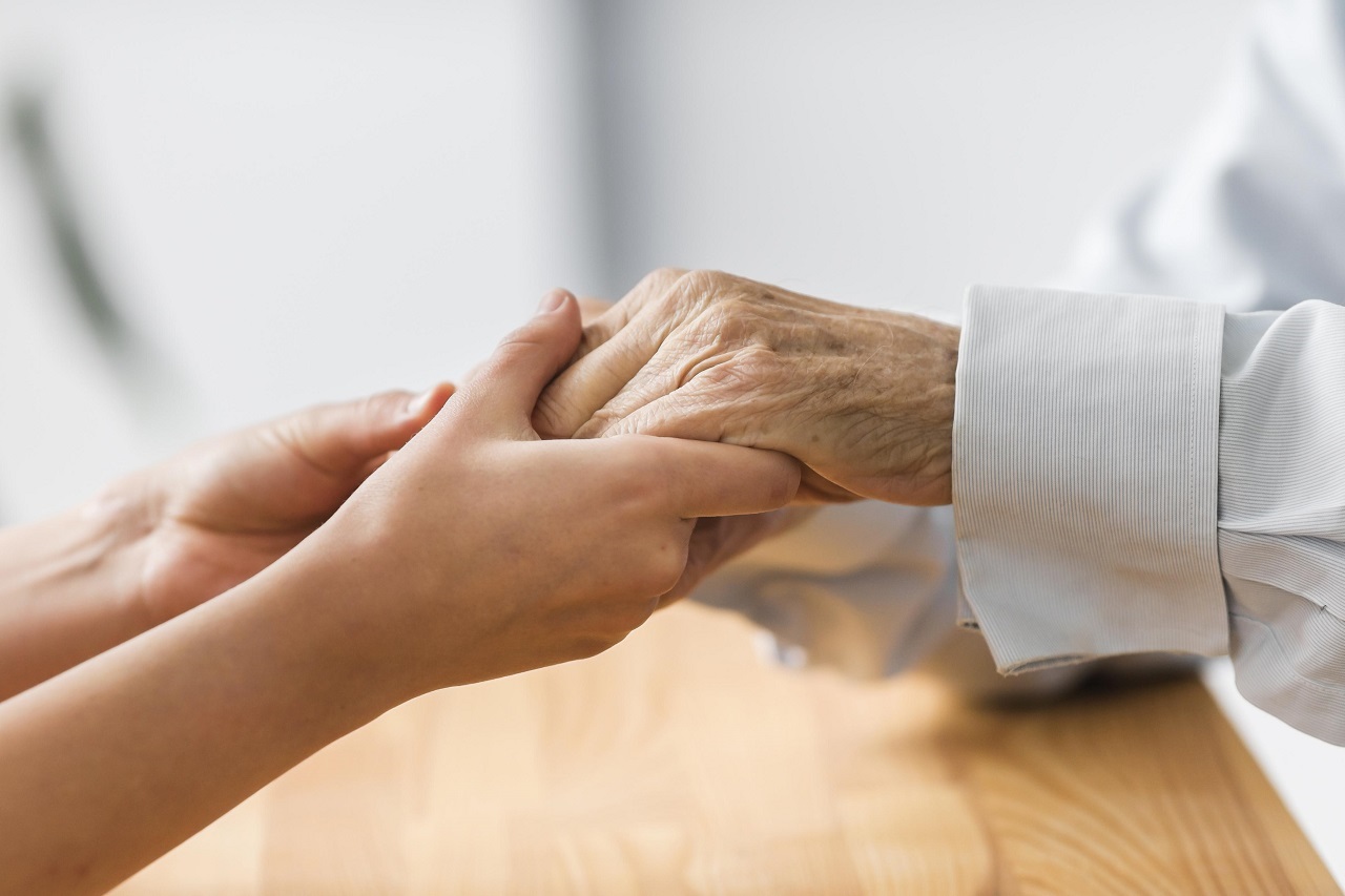 enfermeira segurando as mãos de um utente idoso