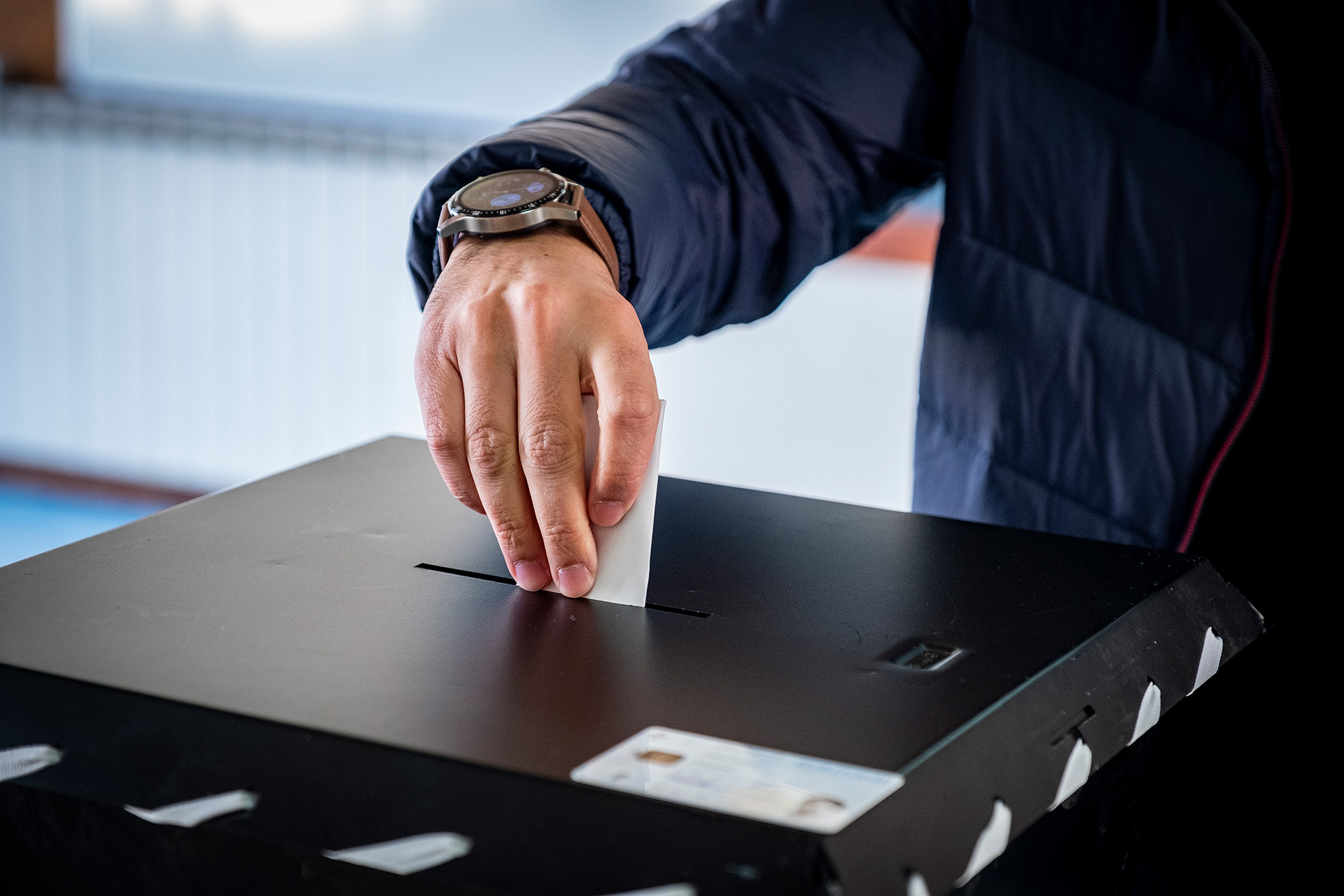 foto de mão a introduzir boletim na urna de voto