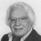 Retrato a preto e branco de um homem idoso, de óculos e cabelo branco, vestido com um casaco escuro e camisola clara.
