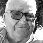 Retrato a preto e branco de um homem idoso com óculos, fotografado ao ar livre.