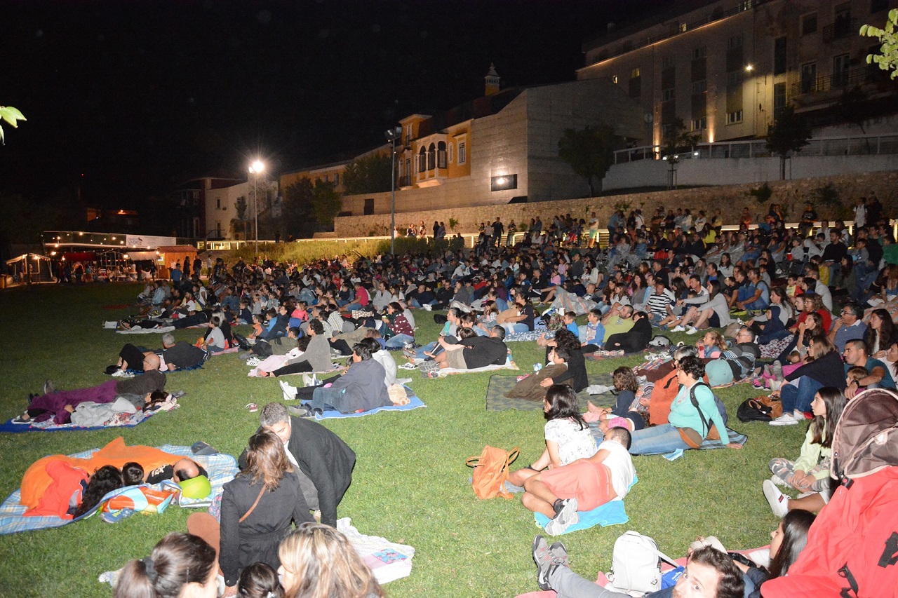 foto noturna do jardim da vala real em Leiria com dezenas de pessoas a assistir a uma sessão de cinema ao ar livre