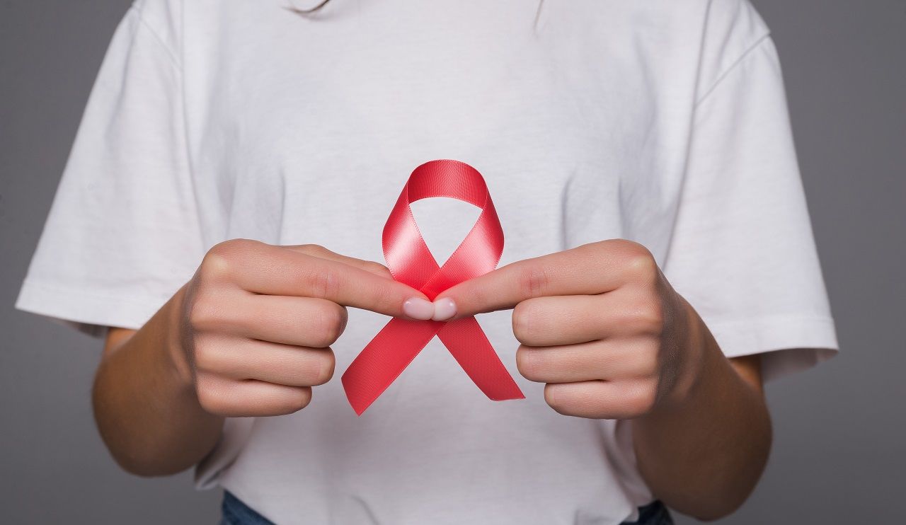 foto de mulher de t-shirt branca a segurar nas mãos um laço cor de rosa