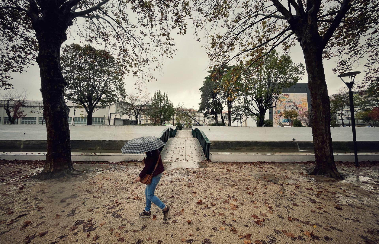 senhora com guarda-chuva a passear no parque do avião em Leiria