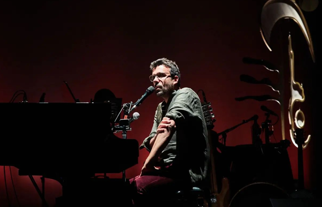 fotografia do músico Miguel Araújo sentado num palco