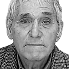 Retrato a preto e branco de um homem idoso, de frente para a câmara. Veste uma camisola aos quadrados.