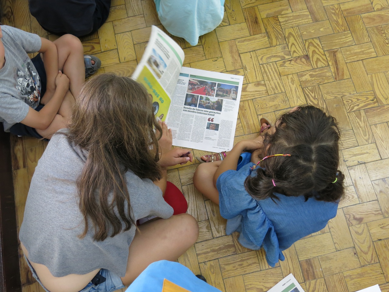 foto de duas crianças sentadas no chão a folhear o região de leiria