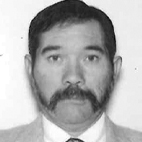 Retrato a preto e branco de um homem com cabelo curto, bigode e barba. Veste um casaco, camisola e gravata.