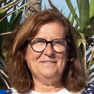 Retrato de uma mulher de óculos, fotografada ao ar livre, com vegetação ao fundo. Não há texto visível que permita identificá-la.