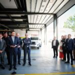 Um homem discursa ao microfone perante um grupo de pessoas no interior de um quartel de bombeiros. Ao fundo, veem-se uma viatura dos bombeiros e um veículo todo-o-terreno.