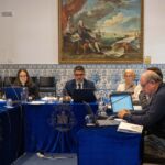 Várias pessoas estão sentadas numa sala de reuniões, com computadores, documentos e microfones. Nas mesas vê-se o brasão e o nome de Pombal.