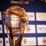 A imagem mostra um troféu dourado com a inscrição «Liga Portugal», diante de um painel de patrocinadores. Não há pessoas identificáveis na imagem.