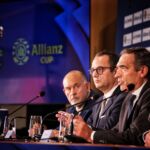 Quatro homens estão sentados numa mesa de conferência, com microfones à frente. À esquerda, vê-se um troféu e, no fundo, o logótipo «Allianz CUP».