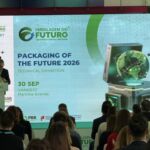Um orador discursa perante uma plateia, junto a um ecrã que anuncia a exposição técnica «Packaging of the Future 2026», em 30 de setembro, na Vangest, Marinha Grande. São visíveis os logótipos de várias entidades patrocinadoras.