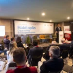 Um orador discursa perante uma plateia numa conferência da Região de Leiria. O painel apresenta o tema «Habitação: O que temos e o que precisamos».