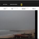 Captura de uma página de webcam da Praia da Vieira, com vista para o areal, o mar e a ondulação. A página apresenta dados sobre vento, temperatura da água e maré.